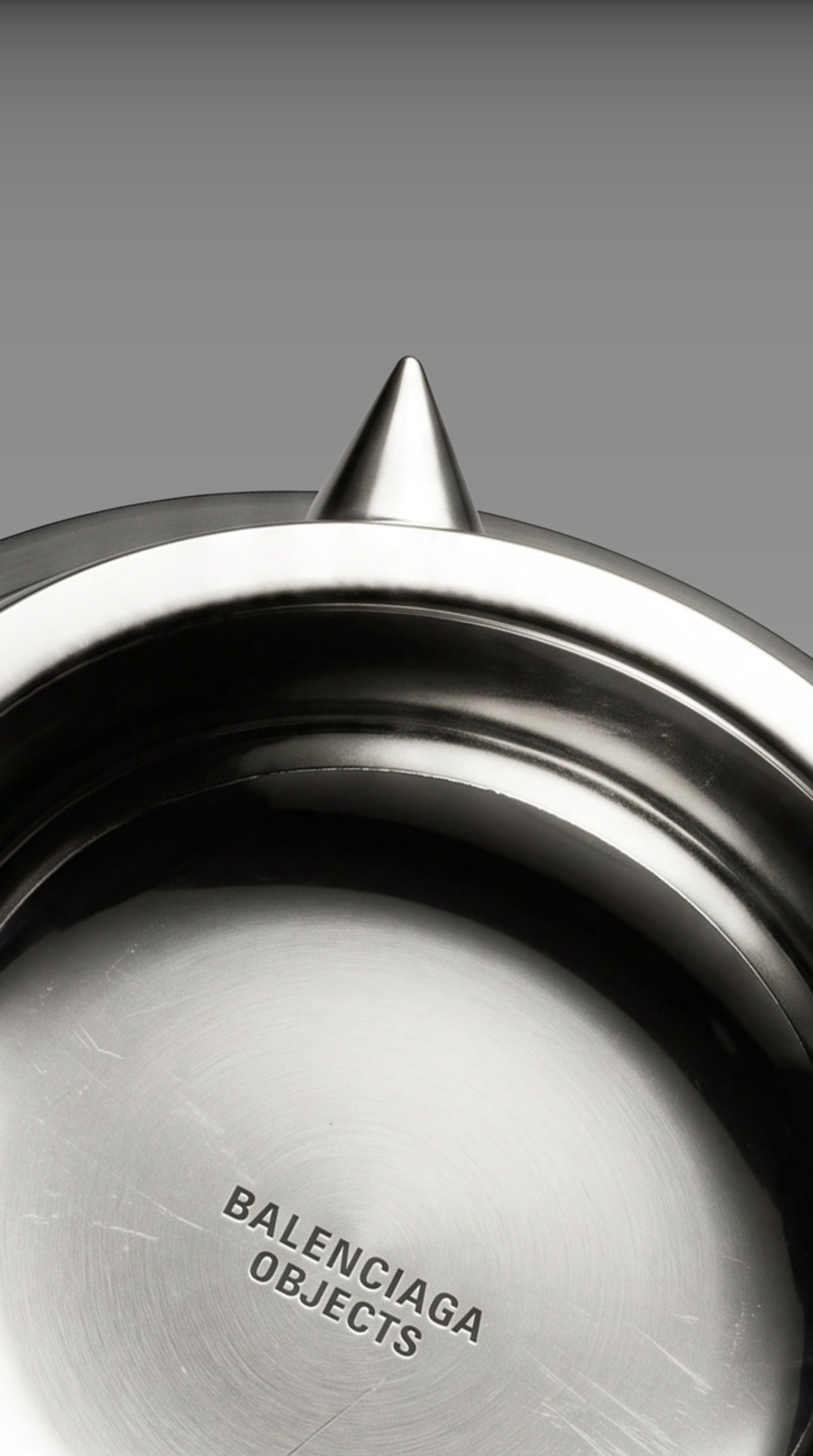 Single Balenciaga-engraved silver fang against a deep black backdrop