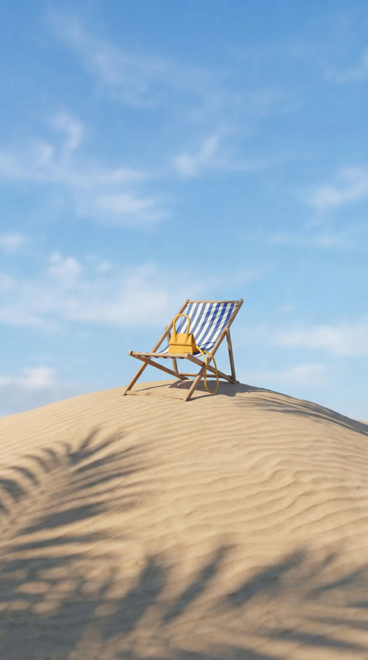 Wide shot of a striped deckchair on top of a sand dune with the bag, under palm shadows