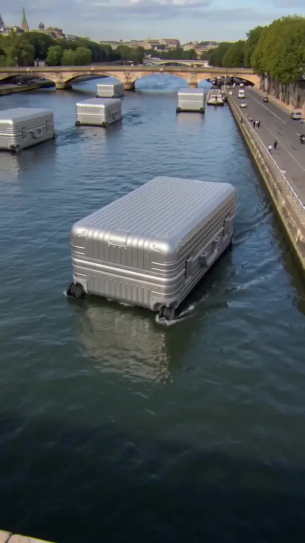 Giant aluminium cases sailing down the Seine in Paris, Eiffel Tower in the distance